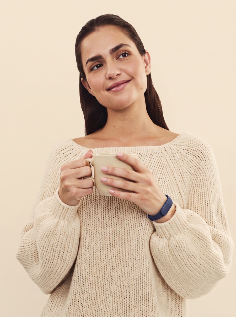 A woman with a warm mug lost in thought, the Larkin band on her wrist