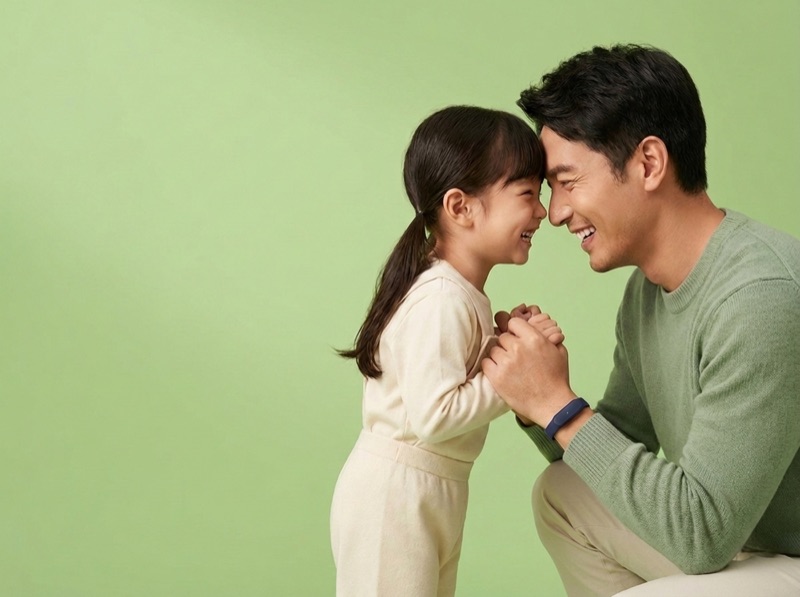 A father and daughter laughing together at eye level, the slim navy Larkin band on his wrist