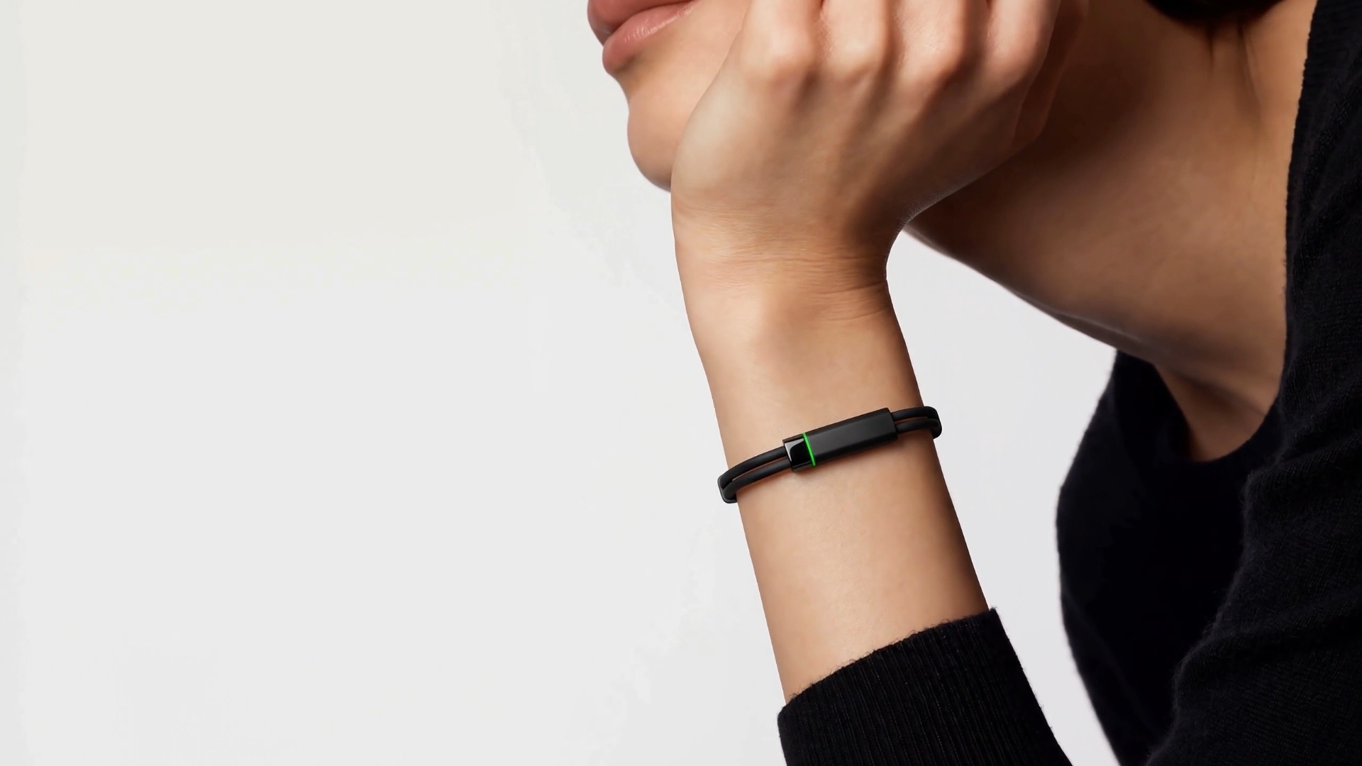 The Larkin band on a woman's wrist, its green light on, as she rests her chin on her hand