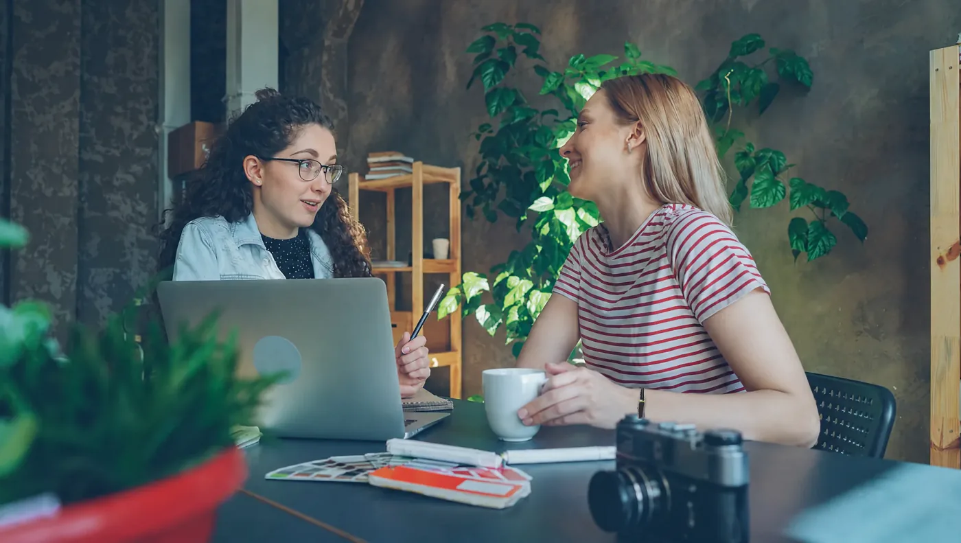 Two friends talking over coffee at a table, the black Larkin band on one woman’s wrist